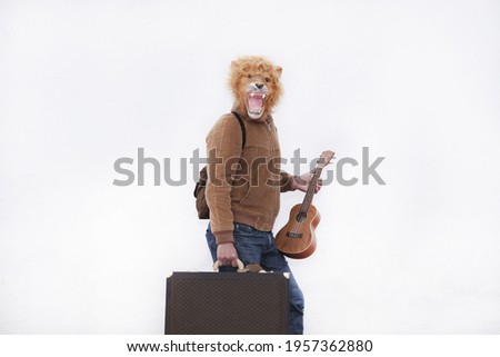 A man with a roaring lion full mask with a brown briefcase and ukulele isolated on white background