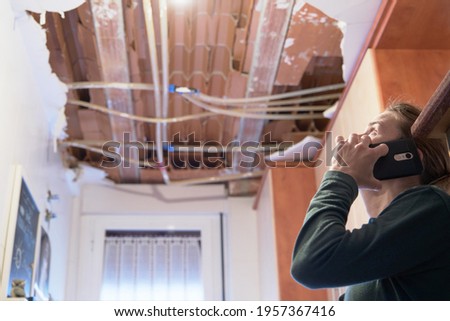Woman talking to homeowner's insurer while inspecting kitchen ceiling. Concept of accident at home Royalty-Free Stock Photo #1957367416