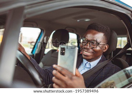Transport, vehicle and technology concept - Smiling man or driver driving car and using smartphone. Dangerous texting and driving at the same time. 