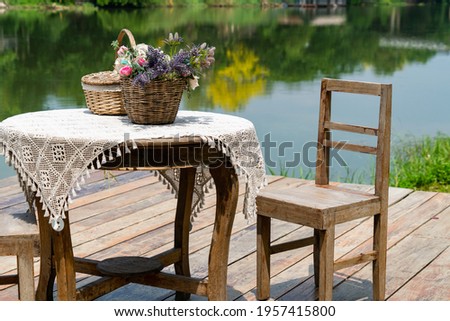 Beautiful decorated table with the basket flower nearby the river side. Relax time, romantic atmosphere nearby the river.
