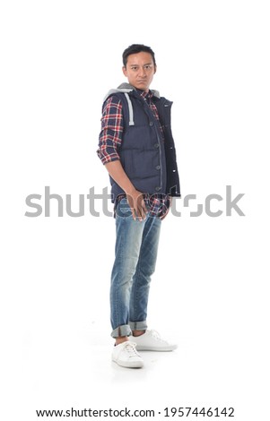 full length portrait of young man in a checkered shirt 
posing in studio

