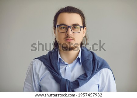 Studio headshot portrait of intelligent nerdy man in office shirt and glasses with moustache and goatee on his serious young face. Photo of college teacher, university professor or IT specialist