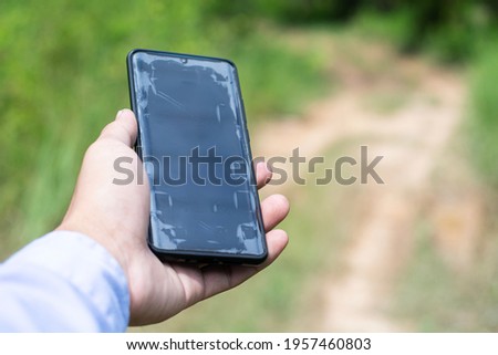 Man using a modern touch phone in the countryside.

