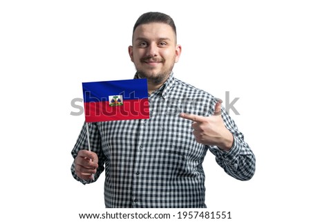 White guy holding a flag of Haiti and points the finger of the other hand at the flag isolated on a white background.