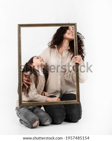 mother and daughter with a frame for a portrait on a white background