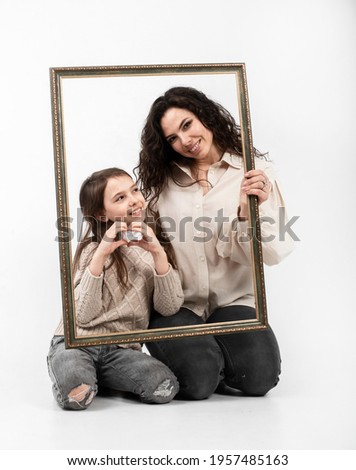 mother and daughter with a frame for a portrait on a white background