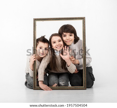 three children, two brothers and sister posing with a photo frame on a white background