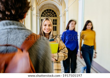 Smiling young girl student from Europe stands with a books at the university old building. Students in the background and foreground. Motion blur. Education, College, school, or University.