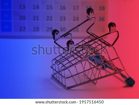 Miniature shopping cart with desktop calendar in neon light. Holiday shopping, black friday, monthly special offer concept 
