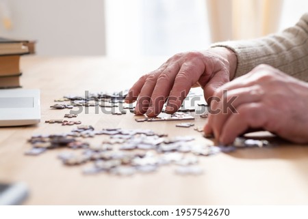 Senior male hands working on a puzzle at home Royalty-Free Stock Photo #1957542670