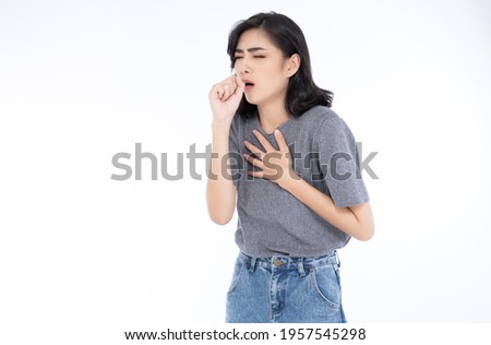Sick young Asian woman in grey t-shirt and jeans feeling unwell and coughing as symptom for cold or bronchitis. Woman have symptoms of COVID-19. Healthcare concept. Royalty-Free Stock Photo #1957545298