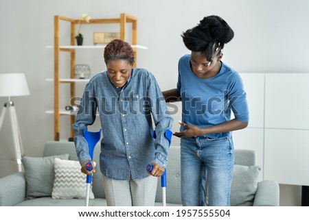 Helping Injured Handicapped African Woman With Crutches Royalty-Free Stock Photo #1957555504