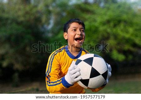 Excited boy football player Holding scored ball Royalty-Free Stock Photo #1957577179