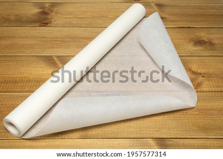 Baking paper roll on wooden table. Royalty-Free Stock Photo #1957577314