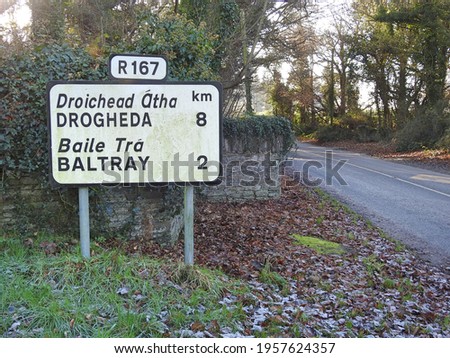 Drogheda and Baltray directional road signs in Termonfeckin in English and translated directly into the Irish language.  Royalty-Free Stock Photo #1957624357