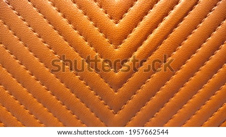 Seams on artificial leather. The thread and arrow stitch seams line the narrow chevron to decorate the bright brown furniture for an interesting and beautiful look. Close focus