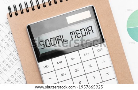 Calculator with text social media with craft colored notepad pen and financial documents.