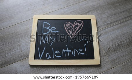 A small blackboard with be my valentine written on it with chalks