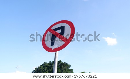 No Parking Sign on Pole with Blue Sky and Trees