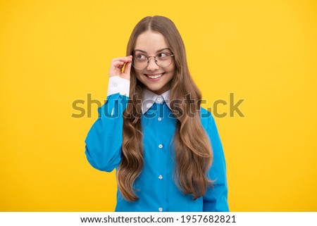 Happy teenage school girl fix eyeglasses smiling yellow background, eyewear.