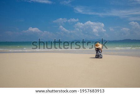 Concept picture of young Asian woman sitting on sand and looking to a sea