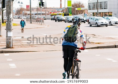 Man with a backpack and helmet crossing the road with a bike by pushing with one leg. Crosswalk. Pedestrian. Cross. Street. City. Outdoor