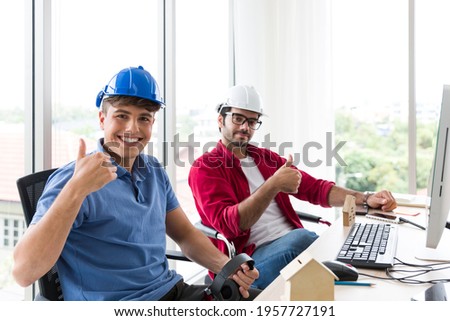 Two engineering man wear helmet working at office desk at work with happy and smile. Group of technical men wear casual working together in the office with desktop computer