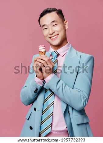 cheerful man in blue suit ice cream in hands smile enjoyment pink isolated background
