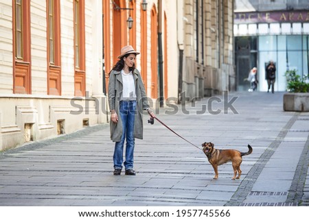 young attractive woman walking her dog on the city street, lifestyle people concept. Beauty woman with her dog playing outdoors
