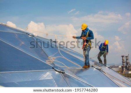 Male two workers rope access height safety connecting with a knot safety clipping into roof fall arrest and fall restraint anchor point systems ready to ascending, construction site oil tank dome. Royalty-Free Stock Photo #1957746280