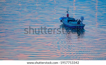 Sunrise in the background as the fishing boat and fishermen leave the harbor - Fishing boat with wake at Dawn Sea of Mediterranean