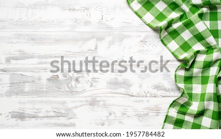 White wooden table covered with green tablecloth. View from top. Empty tablecloth for product montage. Free space for your text