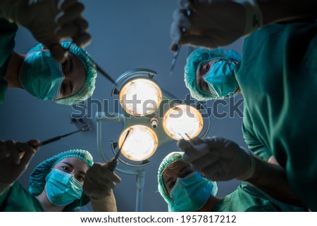 Team of surgeons with scalpel are operation together on background of surgical lamp,Point of view shot.