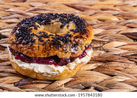Freshly made and baked bagel with cream cheese and strawberry jam. Pastry and home cooking concept. Horizontal photo and selective focus