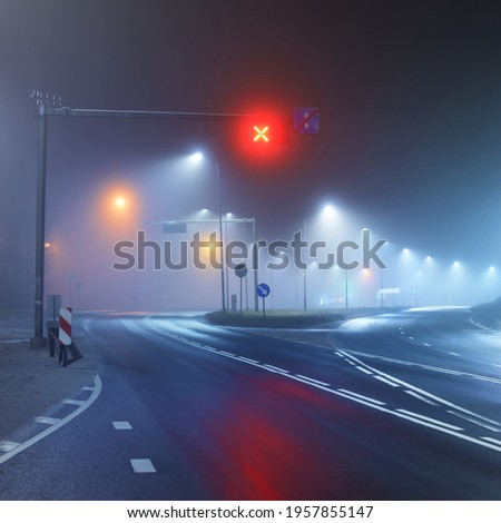 Illuminated empty highway in a fog at night. Street lights and road signs close-up. Dark urban scene, cityscape. Riga, Latvia. Dangerous driving, speed, freedom, concept image