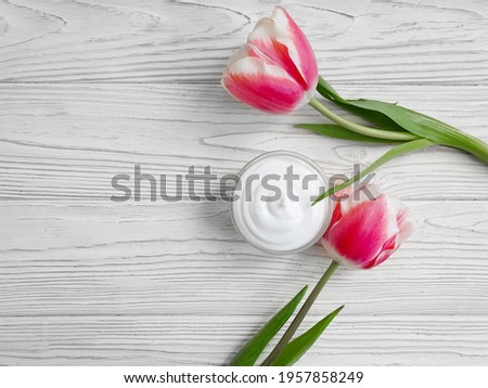 cosmetic cream, tulip flower on wooden background