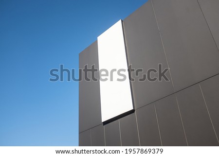 A Sign On The Side Of A Modern Commercial Retail Building, Blank For Your Text, With Blue Sky And Copy Space