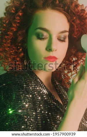 Red-haired white girl wearing a shiny dress, with a microphone in her hands. Rock star and controversial singer