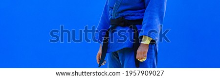 Judo fighter poses in blue kimono with black belt. Japanese judo and jiu jitsu Royalty-Free Stock Photo #1957909027