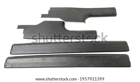 A four of black plastic decorative door sills in an automobile parsing for sale or repair in a workshop on a white isolated background in a photo studio.