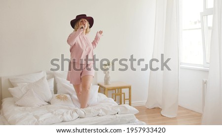 Attractive cheerful woman dancing and singing with comb like microphone at home.