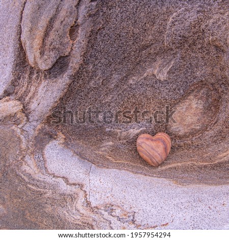 Red stone heart on natural river rock. Love and affection concept.