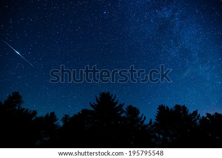 A shot of the milky way and an Iridium flare in the night sky in the Blue Ridge Mountains of North Carolina