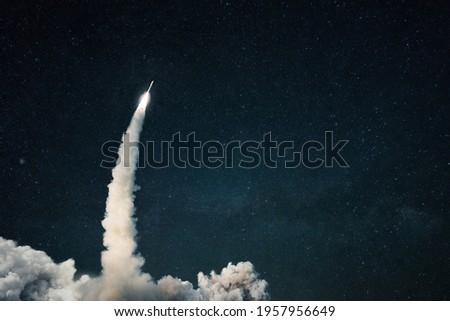 Rocket lift off into space. Spaceship launch with smoke on the starry sky. Space and travel wallpaper. Copy space for design and text Royalty-Free Stock Photo #1957956649