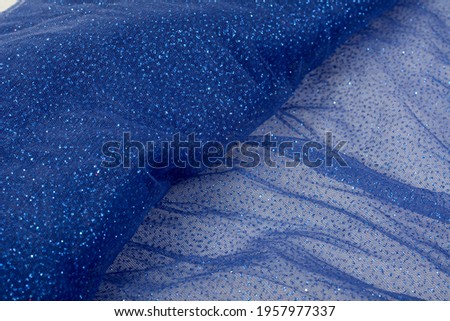 Lightweight Blue Crumpled beautifully draped lace festive tulle fabric with sparkles. texture of wedding clothes, veil, dress, skirt. Use for sew fashion industry with copy space. Close up soft focus