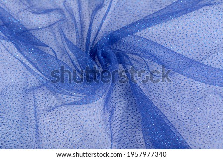 Lightweight Blue Crumpled beautifully draped lace festive tulle fabric with sparkles. texture of wedding clothes, veil, dress, skirt. Use for sew fashion industry with copy space. Close up soft focus