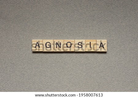 text the word agnosia from brown wooden small letters with black font on an gray table