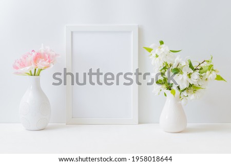 Mockup with a white frame and pink tulips in a vase on a light background