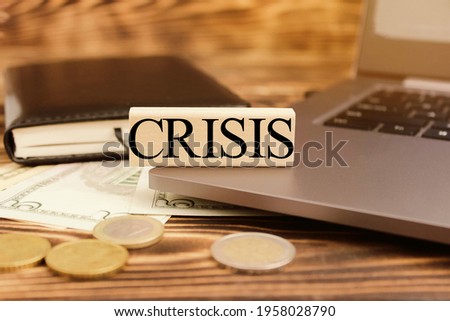 Computer, notebook, pen, crisis, money. Cubes with the word "crisis" on the computer in the office. High quality photo