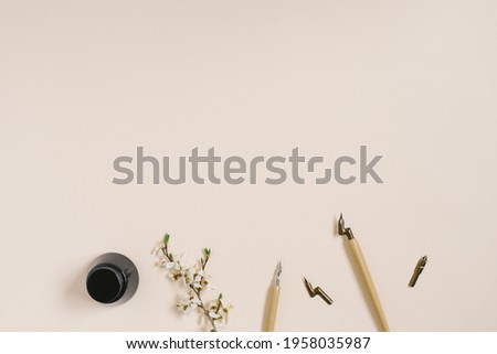 Calligraphy, sharp pen, ink, feather, flower of Apple trees on a beige background with copy space
